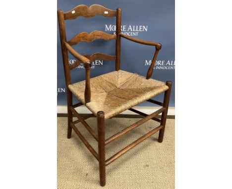 An Arts and Crafts ash framed ladder back rush seat elbow chair in the manner of William Morris, raised on turned legs united