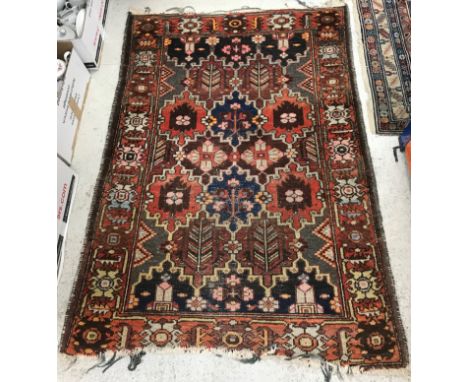 A Persian rug, the central panel set with tiled design, each set with floral spray, within a stepped red scrolling border, ap