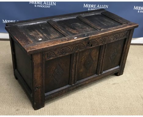 A late 17th Century oak coffer, the three panel top with moulded stiles over a floral lunette carved frieze and three lozenge