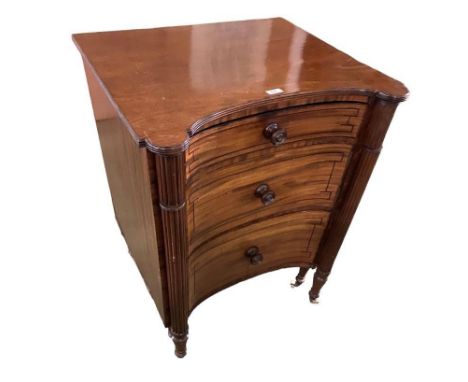 A large Regency  mahogany inverted bow front commode with reeded columns and turned raised legs to castors, with a pull out c