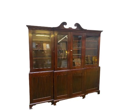 A large late C19th mahogany three sectioned glazed library bookcase, the top with swan neck pediment, with a two door cupboar