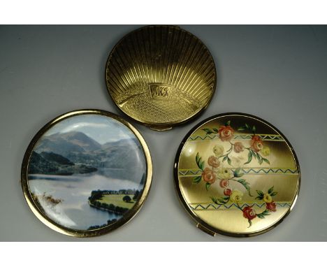 Two gilt powder compacts together with a lake scene compact