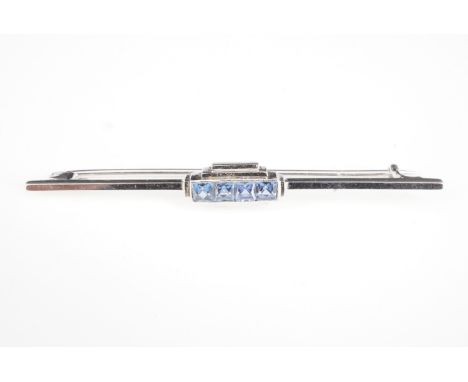 An Art Deco sapphire and precious white metal bar brooch, comprising four square cut stones in a millegrain channel setting, 