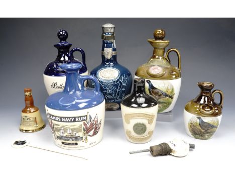A quantity of Wade and other ceramic liquor decanters together with a bottle topper and a stirrer, tallest 23 cm