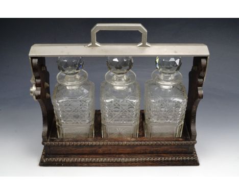 An early 20th Century Betjeman's patent type three decanter oak and electroplate tantalus, circa 1920, (key lacking, though c