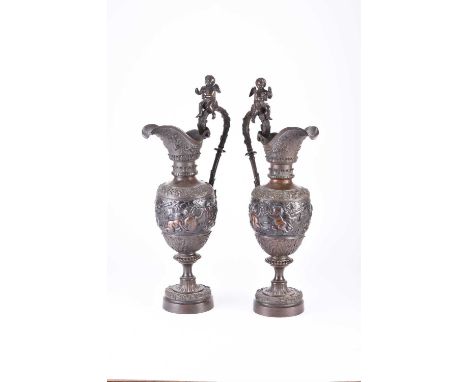 A pair of ornamental bronze wine ewers, late 19th centuryOf amphora shape, the handles surmounted by putti holding cups, the 