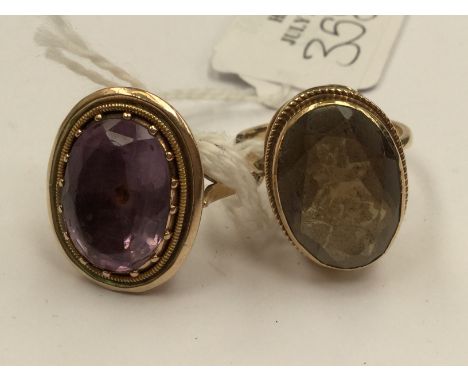 Two yellow metal dress rings, one set with an oval amethyst the other with a smoky quartz, sizes T and R, combined total gros