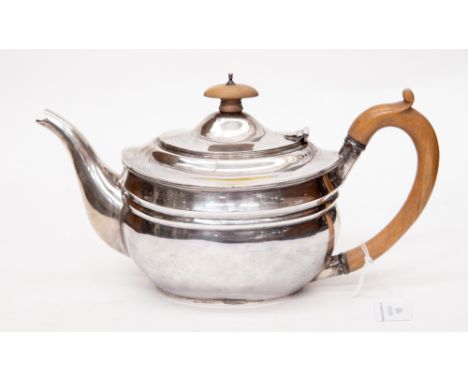 A George V silver teapot of oval form with turned wooden handle and finial, London 1923 