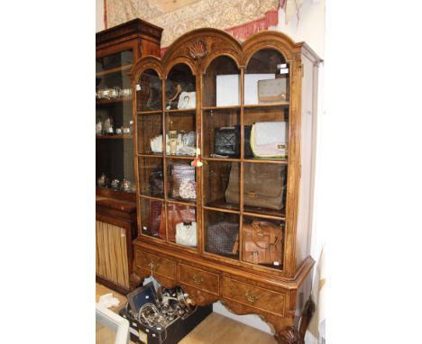 A George I style burr walnut glazed cabinet on stand, arch moulded, eight-light doors above a three drawer base, raised on sh