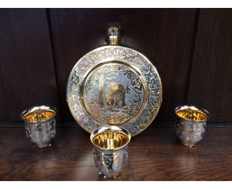 A gilt metal flask, chased design of bears and foliage along with three metal tumblers (4)