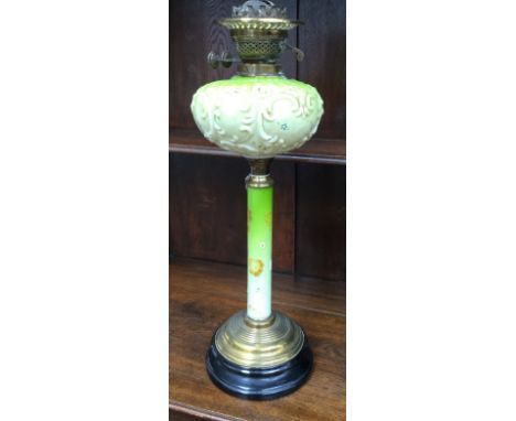 A Vaseline glass oil lamp, having glass reservoir and enamelled glass column on brass and black ceramic base 