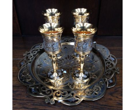 A gilt metal tray, reticulated design with four stemmed metal cups