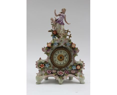 A French style mantle clock, being encrusted with flowers and having woman and child as the finial, ceramic dial with Arabic 