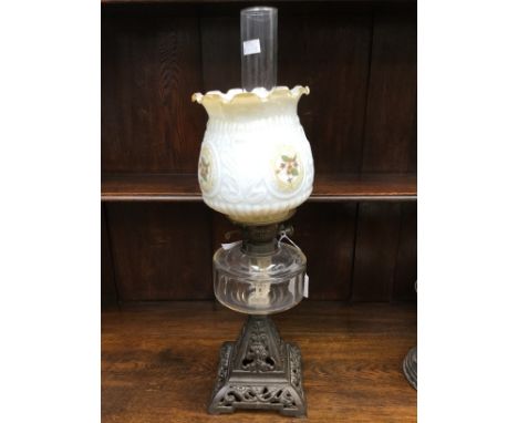 An oil lamp, cast iron base white floral shade, clear reservoir and chimney