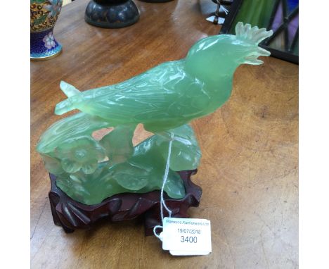 A Jade carved figure of a Peacock raised on a carved wooden base, 15 cm high approx 