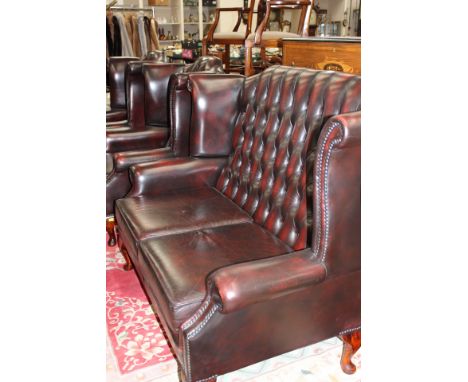 A traditional leather red deep button backed three piece suite, comprising a pair of armchairs and a two seater settee, toget