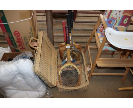 A wicker basket with contents of various vintage tennis rackets