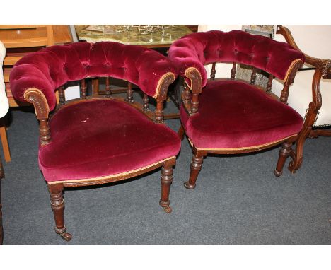 A pair of Victorian tub chairs with button upholstered backs, on balustrade supports, on turned legs and castors