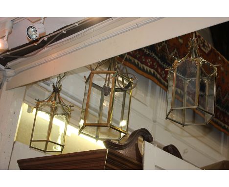 A pair of brass and glass lantern ceiling light fittings, together with a similar larger lantern, 44cm