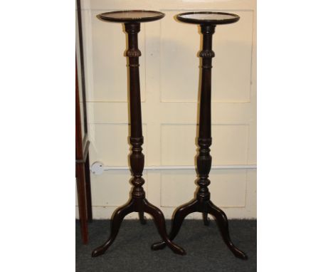 A pair of mahogany torchières, each with circular top on turned baluster stem and outswept tripod legs, 109cm high