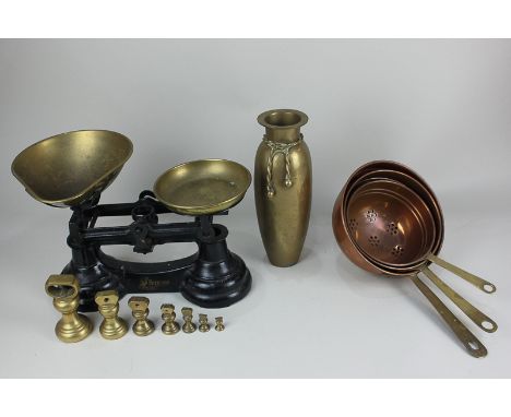 A pair of black cast iron Librasco kitchen scales with brass weights, a set of three copper and brass colanders, and a brass 