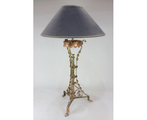 A wrought iron table lamp with scrolling tripod stem and floral decoration, 66.5cm high