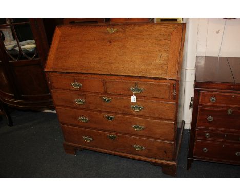 A George III oak bureau with fall enclosing a fitted interior of small drawers and pigeon holes, two short over three drawers