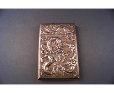 A 19th century white metal card case, embossed with dragons chasing a flaming pearl to one side and figures in a garden aroun