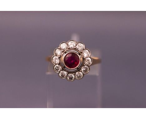 A 1950's ruby and diamond cluster ring, centred with a round mixed-cut ruby approx 0.70cts, millegrain set within an open sur