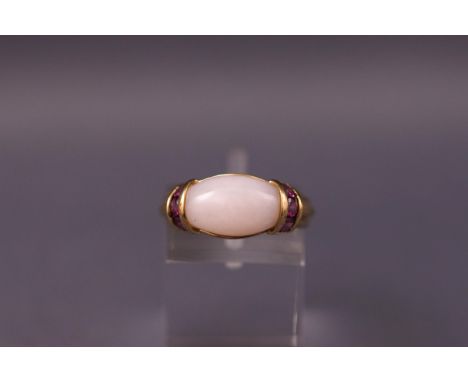 A yellow metal dress ring set with a cabochon rose quartz and rhodolite garnets. Hallmarked 9ct gold. Size K Weight: 3.5 gram