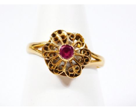 A dress ring, with central pierced floral ring head, set with central ruby, with filigree design petals, with splayed shoulde