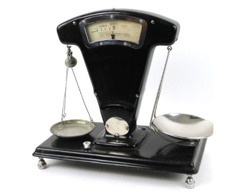 An early 20thC shop scale, in black metal with chrome mounts and metal pans, on shaped supports, 50cm H, 50cm W, 27cm D.