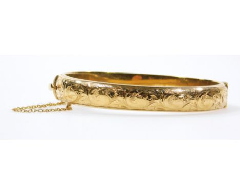 A 9ct gold bangle, of oval outline, partially chased, 8cm wide, 17g.