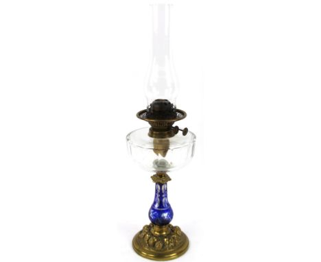 An early 20thC brass and glass oil lamp, with clear funnel and reservoir with baluster stem in blue and white floral pattern 