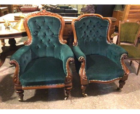 A near pair of Victorian library chairs, both with button backs and arms, in teal upholstery with intricately carved arms, on