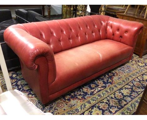 A Chesterfield sofa in red leather with button back and sides, rolled arms, on turned supports (78cm x 192cm x 92cm)