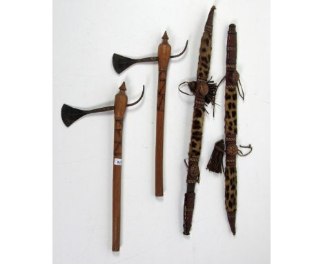 A pair of African engraved steel Axes, with decorated wooden handles, together with a pair of swords with leopard skin covere