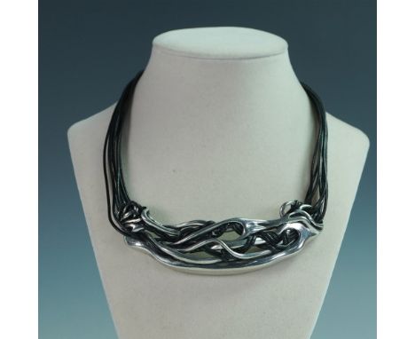 This bold statement necklace features an intricate sculptural metal centerpiece with a freeform, entwined design, giving it a
