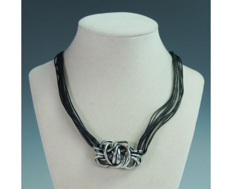 A striking 16-inch necklace featuring multiple strands of black vinyl cord intertwined with a sculptural metal centerpiece. T