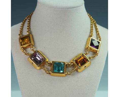 A bold and eye-catching gold-tone necklace featuring square-cut, multi-colored faceted glass stones in bezel settings. The vi