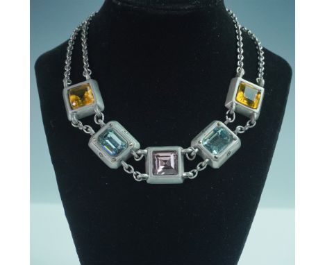 A bold and modern statement necklace featuring square-cut, faceted glass stones in shades of amber, amethyst, and aquamarine,