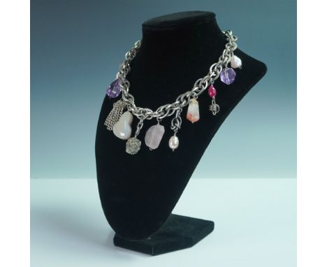 A striking silver-tone 16"L chain necklace adorned with an assortment of eclectic charms and faux gemstones. This unique piec