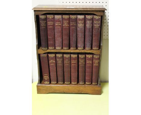 AN OAK TWO SHELF TABLE TOP BOOKCASE CONTAINING SIXTEEN VOLUMES OF CHARLES DICKENS NOVELS .