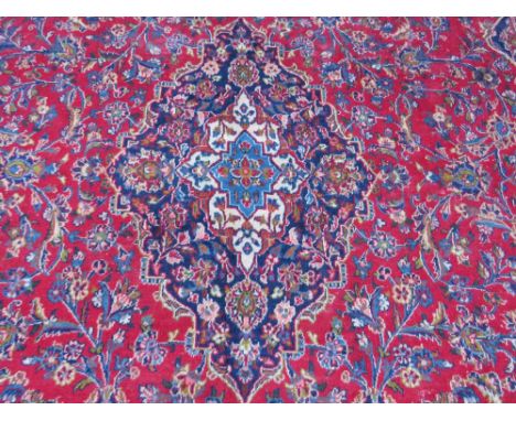 A LARGE RED / BLUE GROUND CARPET, APPROX 389 X 297 CM - WEAR THROUGHOUT