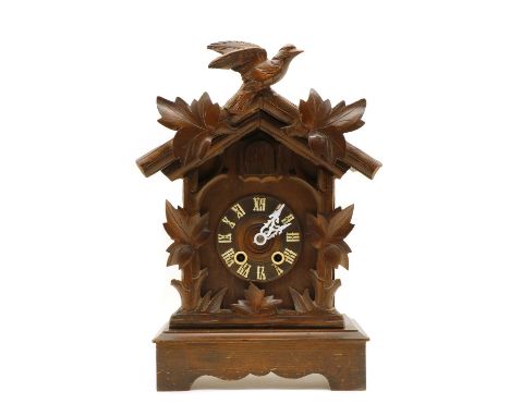 A wooden Black Forest cuckoo clock, with carved bird and leaf decoration, striking the half hours on a gong. 39cm highConditi