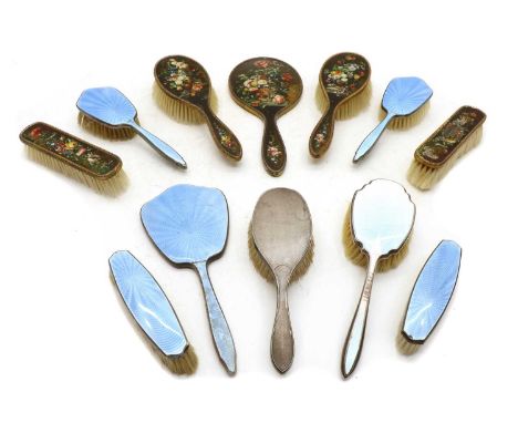 A silver plated and blue enamel five piece dressing table set, a silver gilt five piece dressing table set with floral painte