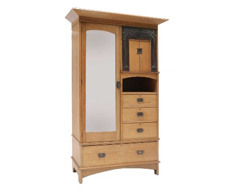 An Arts &amp; Crafts oak single wardrobe, the left side with a mirrored door, opening onto a hanging rail and hooks, the righ