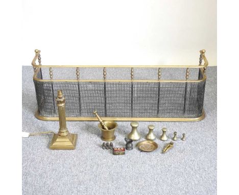 A brass fender, 110cm wide, together with a column table lamp, a Peerage three wise monkey group, metalwares and weights