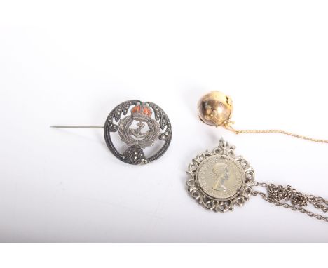 A yellow metal masonic globe watch fob opening to reveal masonic symbols together with a white metal coin pendant on white me