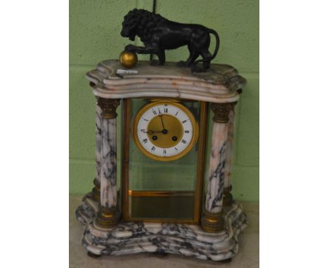 A marble four glass striking mantel clock, surmounted by a lion